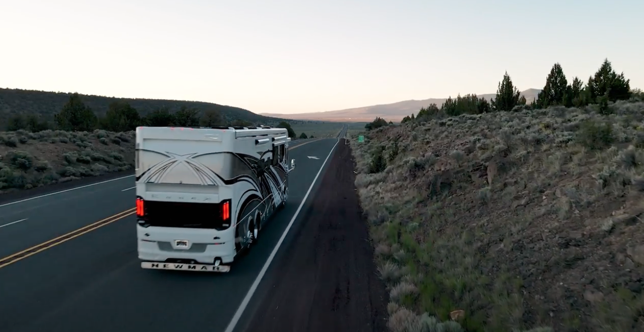RV traveling on an open highway through scenic mountain landscape