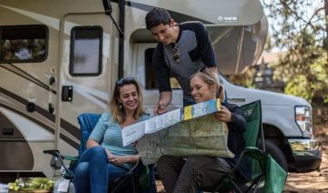 Friends gathered around an RV enjoying outdoor activities